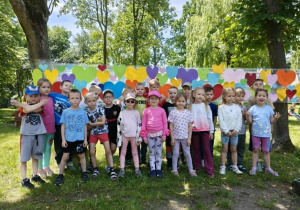 Dzieci z gr 3 pozują na sciance z kolorowych serduszek