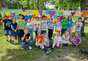 Dzieci z gr 4 pozują na sciance z kolorowych serduszek