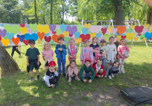 Dzieci z gr 2 pozują na sciance z kolorowych serduszek