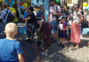 Rodzice z dziećmi czekają w kolejce do loterii fantowej