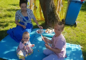 Mama z córkami siedzą na kocu piknikowym