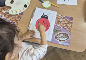 dziewczynka stempluje paluszkiem czarną kropkę na biedronce