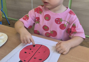 ziewczynka stempluje paluszkiem czarną kropkę na biedronce