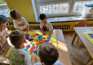 Dzieci tworzą kolorowy kropkowy dywan biorąc udział w zabawie sensorycznej