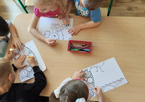 Dzieci kolorują kolorowankę.