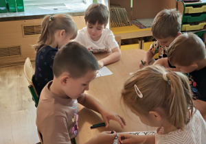 Dzieci kolorują kolorowankę.