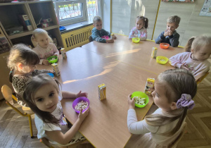 dzieci jedzą przy stoliku popcorn i piją sok