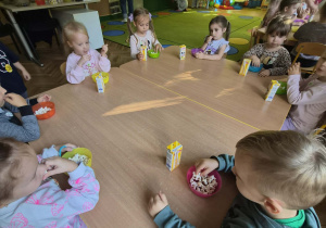 dzieci jedzą przy stoliku popcorn i piją sok