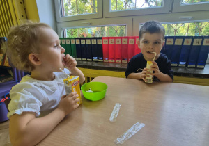 dzieci jedzą przy stoliku popcorn i piją sok