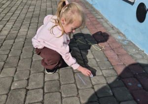 dziewczynka rysuje kredą po kostce
