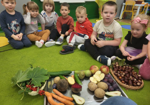 Dzieci siedzą w kole, na srodku jest taca z darami jesieni