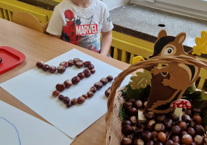 Chlopiec układa kasztany na wzorze.