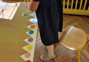 Dziewczynki ozdabiają kołami origami papierowe korony dla chłopców.