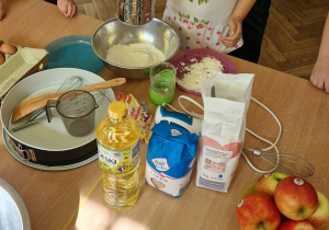 Nauczycielka z dziećmi odmierza produkty na ciasto.