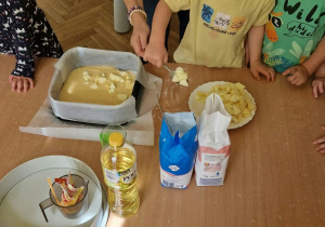 Dziecko wrzuca jabłka do ciasta.