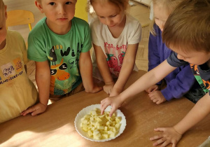 Dzieci zjadają jabłka, który nie zostały wykorzystane do ciasta.