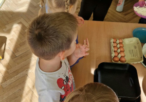 Nauczycielka z dziećmi odmierza produkty na ciasto.
