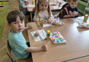 dzieci kosztują babeczkę i soczek urodzinowy