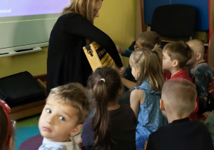 Dzieci siedzą i patrzą na tablicę multimedialną i Panią prowadzącą