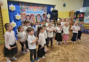 Dzieci w strojach galowych śpiewają i grają na klawesach