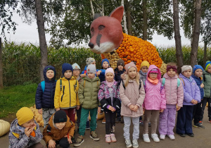 Dzieci stoją na tle lisa z dyń.