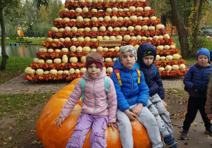 Dzieci siedzą na duże4j dyni.