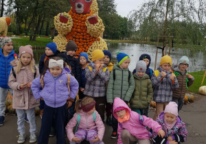 Dzieci stoją przy wiewiórce z dyń.