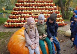 Dzieci siedzą na dużej dyni.