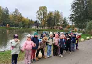 Dzieci stoją na tle stawu.