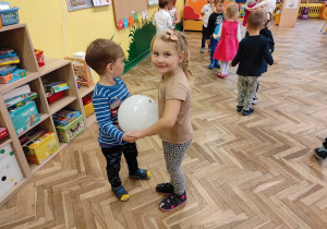 chłopiec i dziewczynka tańczą z balonem w tle widać tańczące dzieci