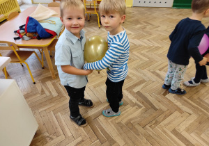 Dwóch chłopców tańczy z balonem