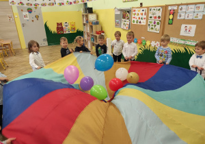 Dzieci bawia się chustą animacyjną na której są kolorowe balony