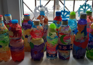 Na parapecie stoi 13 kolorowych butelek z których zrobione są grzechotki