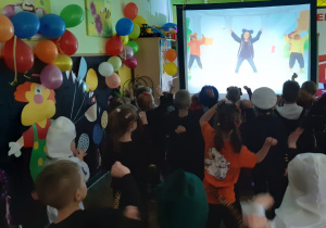 Dzieci tańczą zgodnie z instrukcją podaną na ekranie