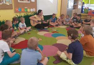 W kole siedzi 18 dzieci oraz Pani która gra na gitarze, wszystkie dzieci śpiewają piosenkę
