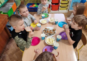 Dzieci siedzą przy stole i kosztują smakołyków