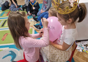 Dziewczynka podpisuje się swoim imieniem na balonie