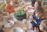Dzieci siedzą przy stole i degustują słodkie przekąski urodzinowe