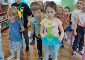 Dzieci przenoszą plastikową butelkę z wodą na plastikowym krążku