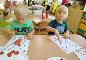 Dwóch chłopców maluje dłońmi szablon zająca