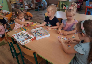 Dzieci siedzą przy stole i układają puzzle