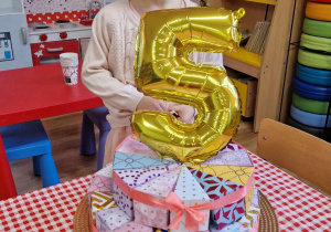 Jubilatka prezentuje swój tort i balon z liczbą 5