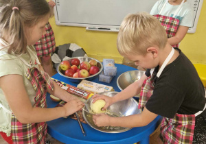Grupa dzieci trze jabłko na tarce