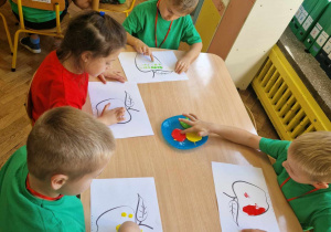 Dzieci malują palcem umoczonym w farbie kontur jabłka