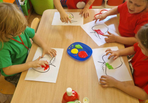 Dzieci malują palcem umoczonym w farbie kontur jabłka