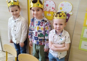 rzech jubilatków w koronach stoi w przedszkolnej sali.
