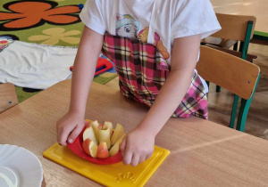 Dziewczynka kroi jabłko na deseczce