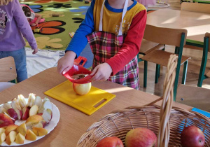Chłopiec kroi jabłko na deseczce