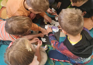 Dzieci układają w małych grupach puzzle z obrazkiem poczty
