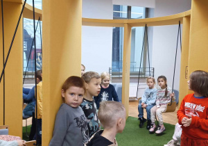 Dzieci bujają się na huśtawkach w sali Na Polanie.
